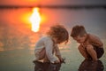 Two little children playing on the beach during sunset. Reflection in water Royalty Free Stock Photo