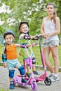 Two little children on scootes and teenage girl in Royalty Free Stock Photo