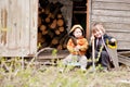 Two little children sit near a shed