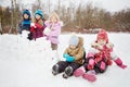 Two little children sit on snow and another three stand aside Royalty Free Stock Photo