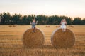 Two little children sitting on a haystack in a field of wheat  at sunset Royalty Free Stock Photo