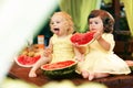 Two little curly girls eating a juicy watermelon in the garden. Children eat fruit on the street. Healthy food for children. Royalty Free Stock Photo