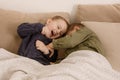 Two little and cute caucasian boys playing together on the bed at home. Interior and clothes in natural earth colors