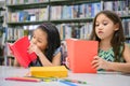 Two little cute girls multi-ethnic friends reading books together in school library. People lifestyles and Education learning Royalty Free Stock Photo