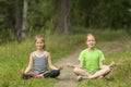 Two little cute girls sitting in the Lotus position in the Park. Royalty Free Stock Photo