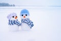 Two little cute snowmen in hats and scarves on the snow on a winter day Royalty Free Stock Photo