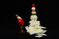 Two little decorative christmas figures from metal, a king and a snowman, the snowman stands up on a heap of white snow of sugar m