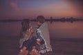 Two little friends, boy and girl talking and drinking tea while sitting covered with blanket by the river. sunset Royalty Free Stock Photo