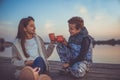 Two little friends, boy and girl talking while sitting and drinking tea by the lake Royalty Free Stock Photo