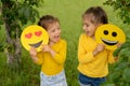 Two little funny girls are holding smile faces with different emotions