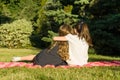 Two little girlfriends embracing sitting on a meadow in the park. View from the back Royalty Free Stock Photo