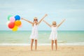 Two little girls with balloons standing on the beach at the day