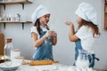 Two little girls in blue chef uniform having fun and preparing food on the kitchen