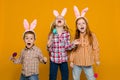 Two little girls and boy with Easter bunny ears holding colorful eggs Royalty Free Stock Photo