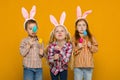 Two little girls and boy with Easter bunny ears holding colorful eggs Royalty Free Stock Photo