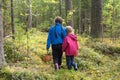 Two little girls carrying wicker baskets for gathering mushrooms and berries hiking in a forest in fall season