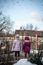 Two little girls in the countryside watching a flock of birds