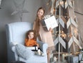 Two little girls with gifts standing near a stylized Christmas tree Royalty Free Stock Photo