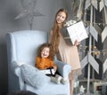 Two little girls with gifts standing near a stylized Christmas tree Royalty Free Stock Photo