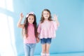 Two little girls girlfriends sisters portrait on a blue background