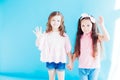 Two little girls girlfriends together on blue background