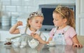 Two little girls having a princess tea party at home. Siblings or friends wearing tiaras while playing with tea set and