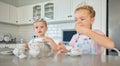 Two little girls having a tea party at home. Sibling sister friends wearing tiaras while playing with tea set and having