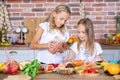 Two little girls in the kitchen with fresh vegetables. Healthy food concept. Happy sisters. Royalty Free Stock Photo