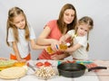 Two little girls at kitchen table with enthusiasm to help my mother to pour vegetable oil in a frying pan