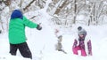 Two little girls playing with a little boy in the snow in winter forest. Royalty Free Stock Photo