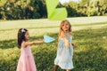 Two little girls playing with a paper plane in summer day in park. Cute kids throwing airplanes outdoors in the garden. Childhood Royalty Free Stock Photo
