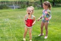 Two little girls playing in a sprinkler on a summer day Royalty Free Stock Photo