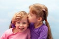 Two little girls, preschoolers, young sisters siblings smliling, laughing. Children kiss on the head concept. Care and love Royalty Free Stock Photo