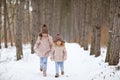 Two little girls run in a snowy winter forest