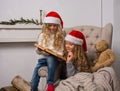 Two little girls in Santa caps are reading a book Royalty Free Stock Photo