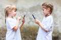 Two little girls, sisters or friends using their smartphones, children texting on their mobile phones facing each other Royalty Free Stock Photo