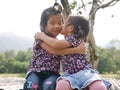 Two little girls, sisters, hugging and kissing on a bench in the evening sunlight - sisters` bond and love Royalty Free Stock Photo