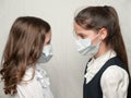 Two little girls sisters in medical mask look at each other very close contact during coronavirus covid-19 epidemic outbreak