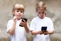 Two little girls, sisters using modern smartphones, young children holding their mobile phones, playing around. New generation