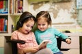 Two little girls sisters wear headphones watching cartoons or kid video on mobile phone Royalty Free Stock Photo