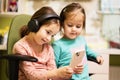 Two little girls sisters wear headphones watching cartoons or kid video on mobile phone Royalty Free Stock Photo