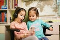 Two little girls sisters wear headphones watching cartoons or kid video on mobile phone Royalty Free Stock Photo