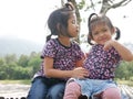 Two little girls, sisters, 3 and 2 years old, kissing on a bamboo bench in the evening sunlight - sisters bond, love, and