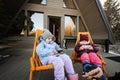 Two little girls sit on chairs at terrace off grid tiny house in the mountains and watching cartoons on mobile phones Royalty Free Stock Photo