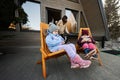 Two little girls sit on chairs at terrace off grid tiny house in the mountains and watching cartoons on mobile phones Royalty Free Stock Photo