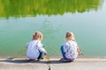 Two little girls are sitting on the shore of the lake. Royalty Free Stock Photo