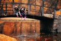 Two little girls sitting on wooden bridge and pretend fishing; autumn background