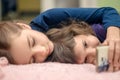 Two little girls with smartphone lying on bed at home and playing mobile games Royalty Free Stock Photo