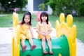 The two little girls smiled a little, sitting on a tube of yellow-green players. An Asian girl is wearing a yellow dress. Child is Royalty Free Stock Photo