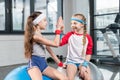 Two little girls in sportswear sitting at fitness studio Royalty Free Stock Photo